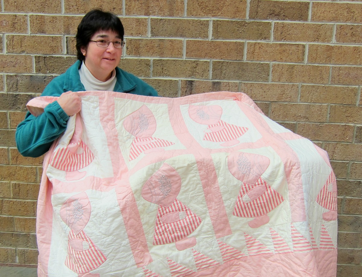 Cat's Meow staffer, Danette, showing off her Sunbonnet Sue quilt made by her grandmother
