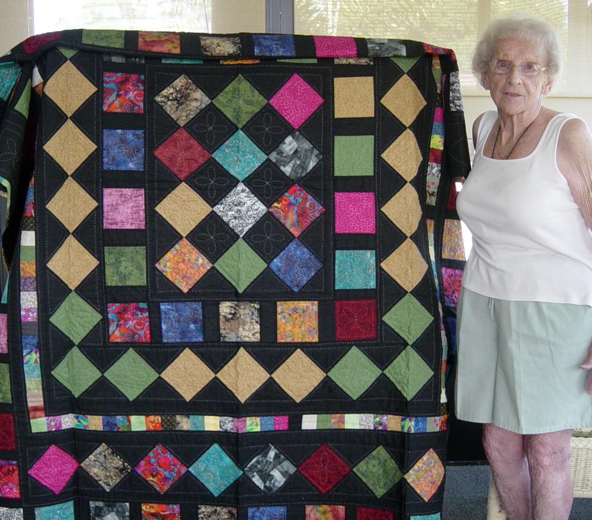 The grandmother of Cat's Meow staffer, Brent, showing off the Magic Carpet quilt she made for Brent and his wife.